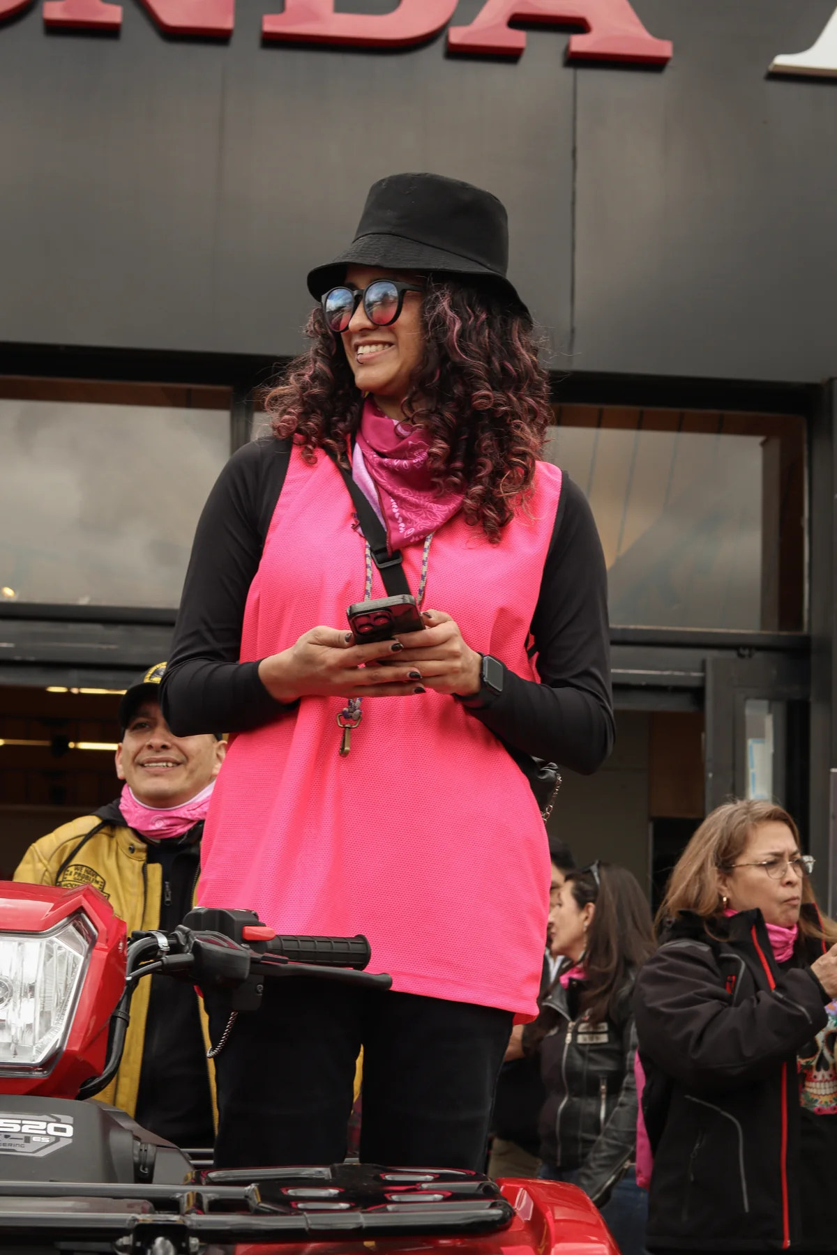 Luseliss sonríe con su chaleco y pañoleta rosa durante un encuentro de la comunidad.