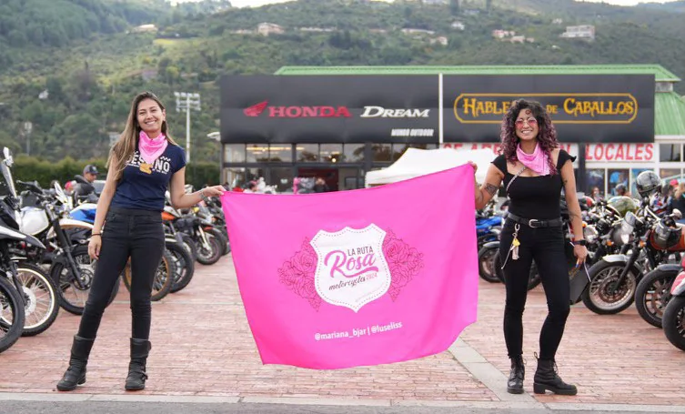 Dos participantes sostienen la bandera de La Ruta Rosa durante la primera edición, en octubre de 2024.